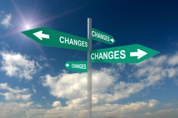 Image of sign post against a blue cloudy sky showing 4 arrows pointing to "change"